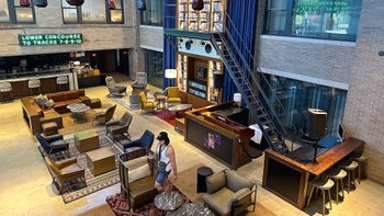 Blick auf eine weitläufige moderne Hotellobby in einem ehemaligen Bahnhofsgebäude.