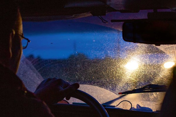 Mann sitzt im Auto und wird von einem anderen Auto geblendet.