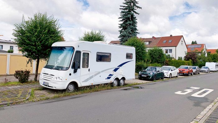 Ein Wohnmobil parkt am Straßenrand in einem Wohngebiet.