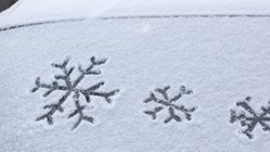 Schneebedeckte Autoscheibe mit Schneeflockensymbolen.