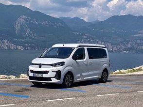Ein weißer Citroën Holidays parkt vor einem See.
