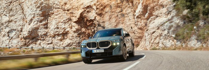 BMW fährt auf einer Straße durch eine bergige Landschaft.