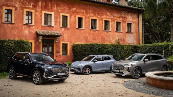 Drei Autos, die vor einem Haus stehen.