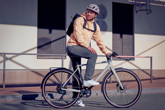 Mann mit Fahrradhelm sitzt auf einem Fahrrad und blickt nach hinten.