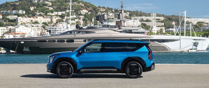 Ein blauer Kia EV9 fährt durch die Stadt.