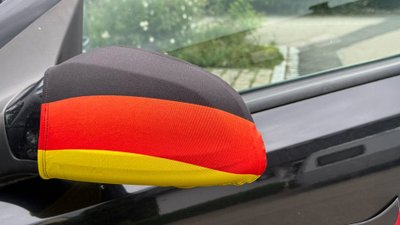 Spiegelüberzieher in Deutschlandfarben schmücken ein Auto.