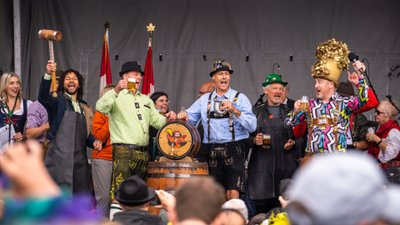 Feiernde Menschen in Tracht stehen mit Bierfass auf einer Bühne.
