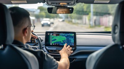 Ein Autofahrer bedient den Touchscreen im Cockpit während der Fahrt.