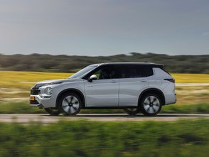 Seitliche Ansicht des Mitsubishi Outlander während der Fahrt auf einer Landstraße.