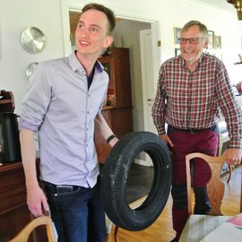 junger und älterer Mann im Haus, jüngerer Mann hält einen Reifen in der Hand.