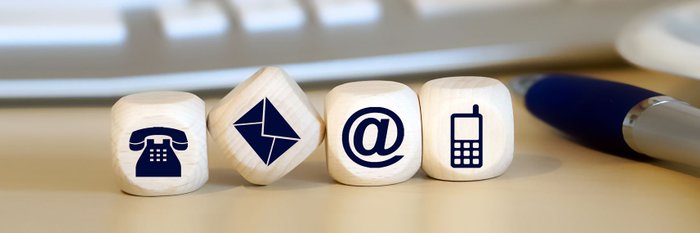Vier Würfel mit den Symbolen Telefon, Mail, @ und Handy.