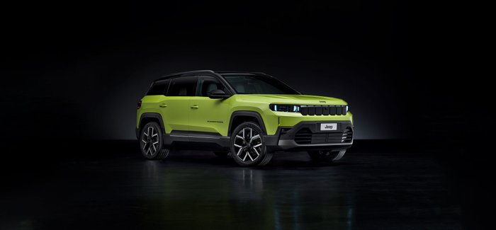 Grüner Jeep Compass vor dunklem Hintergrund.