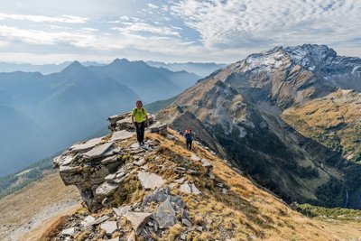 Zwei Wanderer laufen im Hochgebirge über einen Gipfelgrat.