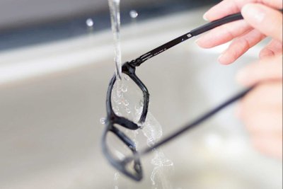 Eine Brille unter einem laufenden Wasserhahn.