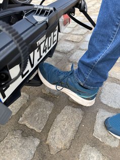 Fuß drückt auf einen Fußhebel am Fahrradträger. 