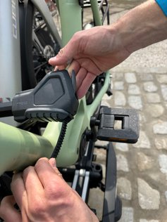 Mann führt Gurt durch einen Haltearm eines Fahrradträgers.