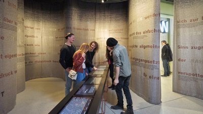 Besucher beugen sich in einem Museum über Infotafeln.