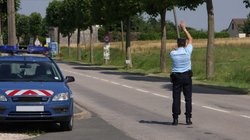 Französischer Polizist steht auf der Straße und hält ein Auto an. 
