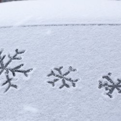 Schneebedeckte Autoscheibe mit Schneeflockensymbolen.