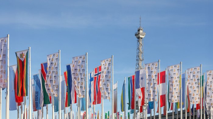 Nationalflaggen verschiedener Länder und Flaggen mit ITB-Logo wehen vor dem Berliner Messeturm im Wind.