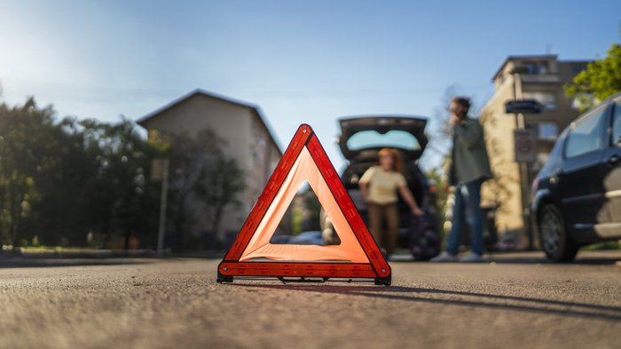 Ein Warndreieck ist vor einem verunfallten Auto aufgestellt. 