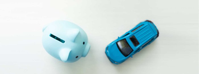 Spielzeugauto neben Sparschwein.