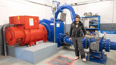 Mann in Skikleidung steht in einer Halle vor Beschneiungsanlage.