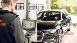 Mann steht an Diagnosegerät vor einem Auto.