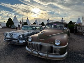 Im Hintergrund eine Siedlung mit Tipis, im Vordergrund Classic Cars.