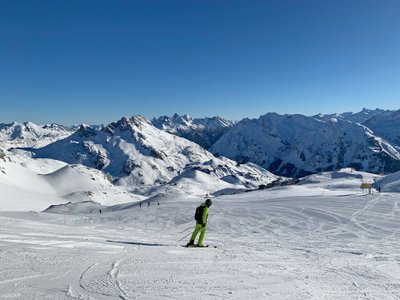 Ein einzelner Skifahrer fährt auf einer präparierte Piste.