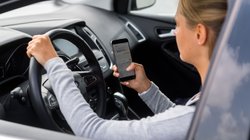 Junge Frau im Auto tippt auf dem Handy. 