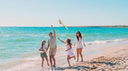 Eine glückliche Familie lässt am Strand einen Drachen steigen.