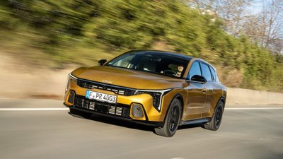 Gelber Kia K4 auf einer Landstraße.  