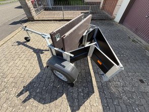 Teilweise zusammengefalteter Faltos-Anhänger steht in einer Einfahrt.