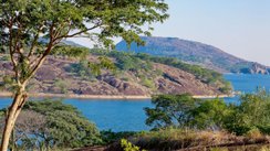 See mit hügeligem Ufer und grünen Bäumen.