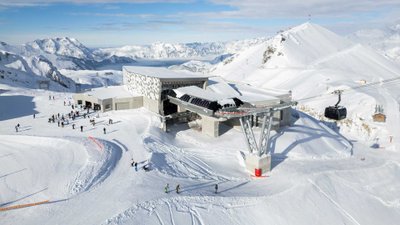 Blick auf die Anlage einer Gondelbahn inmitten verschneiter Bergkulisse.
