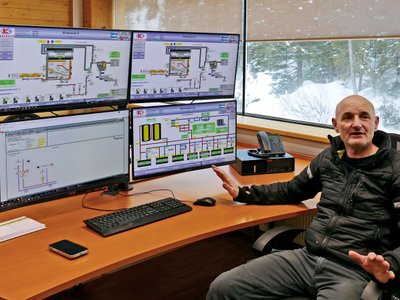 Franz-Josef Schmutzer an seinem Schreibtisch mit Monitoren, die die Daten zur örtliche Wärmeversorgung anzeigen.