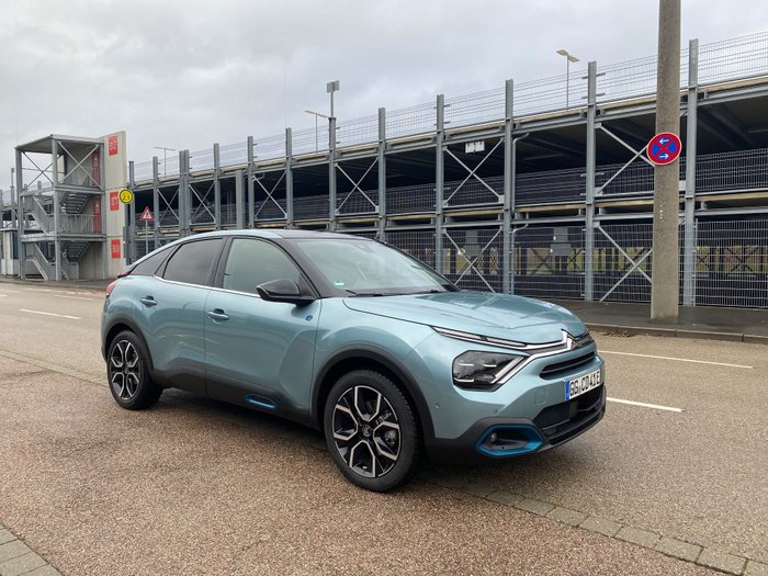 Ein Citroen e-C4-Shine steht vor einem Parkhaus.