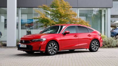 Ein roter Honda Civic 2025 parkt vor einem modernen Bürogebäude.
