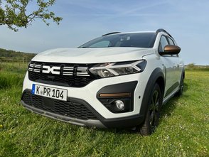 Weißer Dacia Jogger von vorne in einer grünen Landschaft.