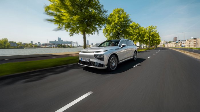 Ein E-Auto Xpeng G9 fährt auf einer Straße mit Bäumen an einem Fluss entlang.