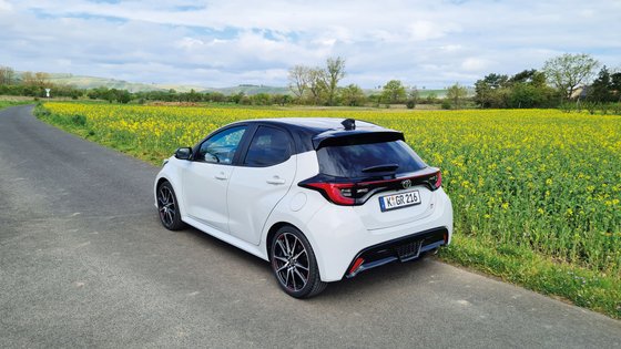 Seitenansicht von hinten eines weißen Auto auf der Landstraße.