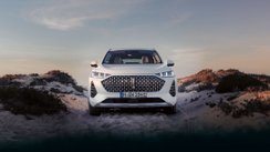 Weißes Auto, welches auf Sanddünen steht.