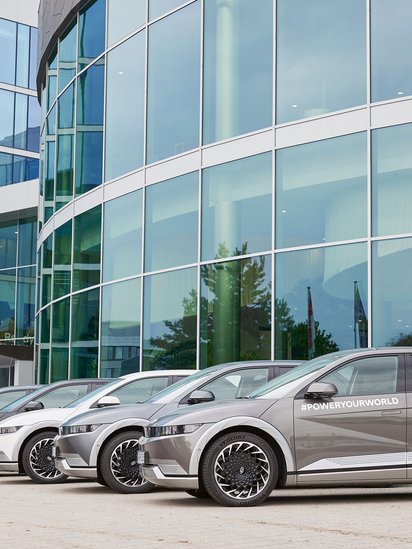Hyundai Autos in einer Reihe vor einem Gebäude mit Glas-Verkleidung.