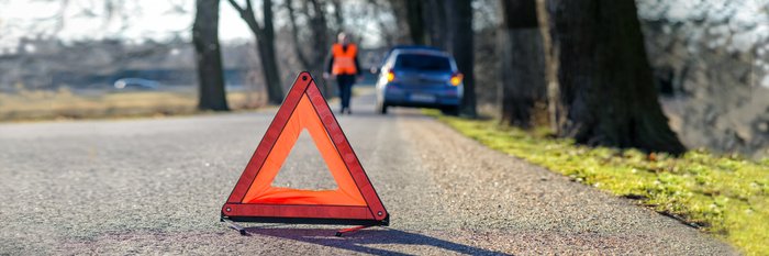 Warndreieck und Pannenfahrzeug auf Landstraße.