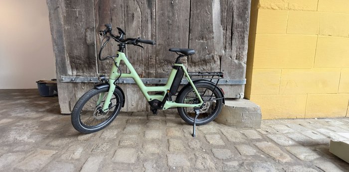 Grünes Fahrrad steht vor einer Holzwand