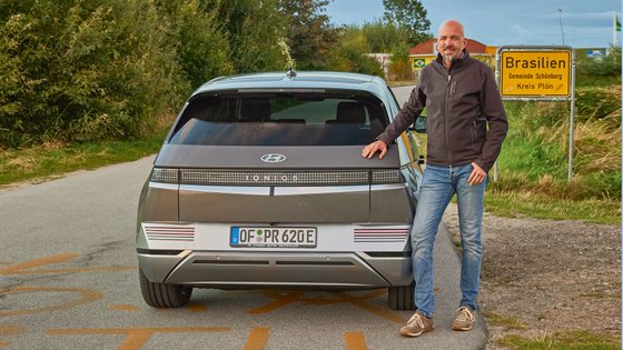 Mann steht neben Hyundai Auto, welches von Hinten zu sehen ist.