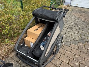 Im Croozer Yuuna liegen Kartons und ein Baby.