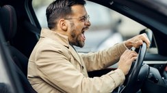 Wütender Mann sitzt im Auto und drückt auf die Hupe. 