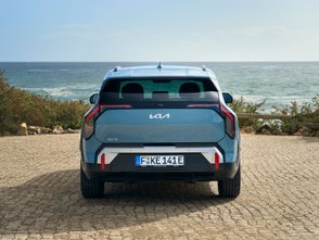 Blauer Kia EV3 steht auf einem Platz am Meer. 
